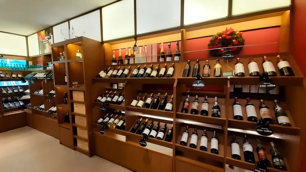 Interior toko wine Peakwine dengan rak botol dan pencahayaan hangat