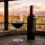 Gelas kristal berisi wine Malbec merah keunguan pekat dengan pantulan cahaya magenta dan botol elegan di atas meja kayu sommelier