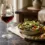 Segelas crystal red wine di samping hidangan salad mediterania segar di meja marmer hangat