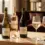 Deretan botol wine manis elegan Moscato berkilau dan Sweet Red di atas meja marmer krem dengan gelas kristal berembun dingin
