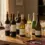Koleksi kurasi botol red wine, white wine, dan sparkling wine berkualitas di atas meja kayu dengan pencahayaan hangat